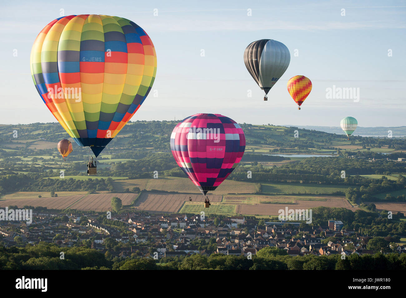 I palloni ad aria calda attraverso la deriva di Somerset campagna durante la salita di massa, dove mongolfiere provenienti da tutto il mondo si riuniranno a Ashton Court, Bristol, a prendere parte al Bristol International Balloon Fiesta. Foto Stock