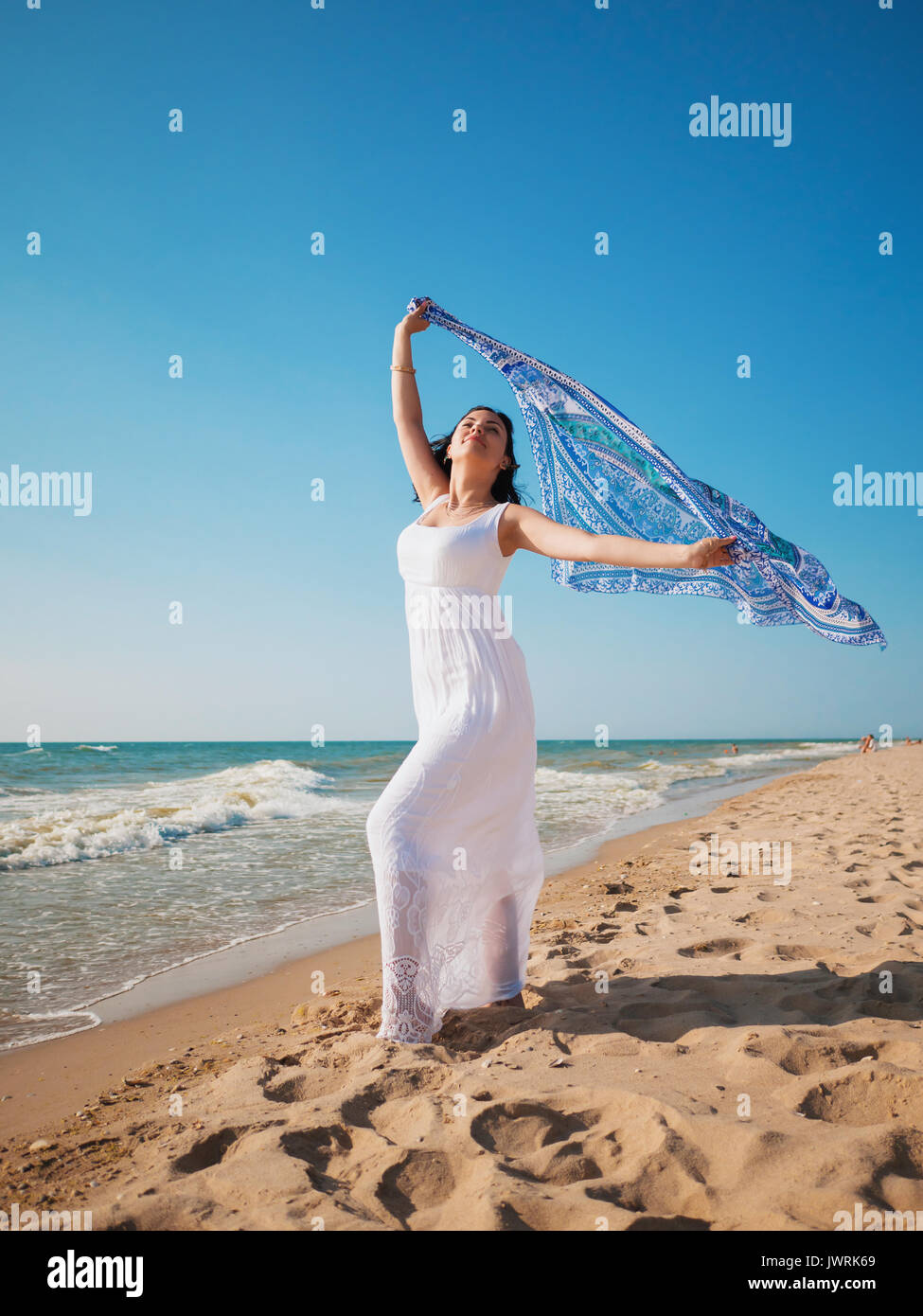 I giovani zingari brunette Girl indossando maxi bianco abito lungo in piedi  sul mare o oceano beach con mandala foulard di seta in mani. Bohemian stile  di abbigliamento Foto stock - Alamy