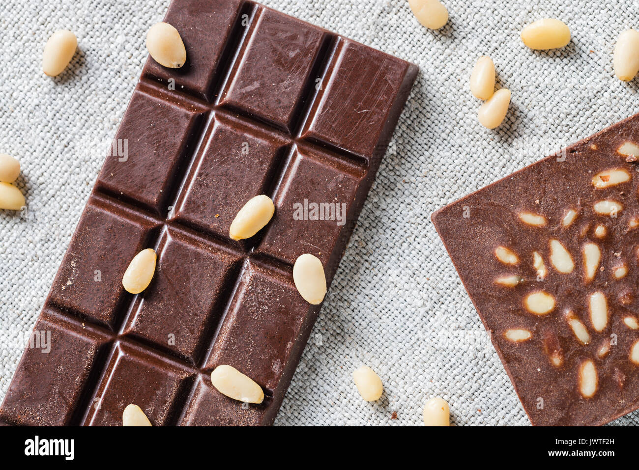Barre di materie vegan cioccolato artigianale con semi di pino su tela dello sfondo. Concetto vegetariana di alimenti sani. Vista superiore Foto Stock