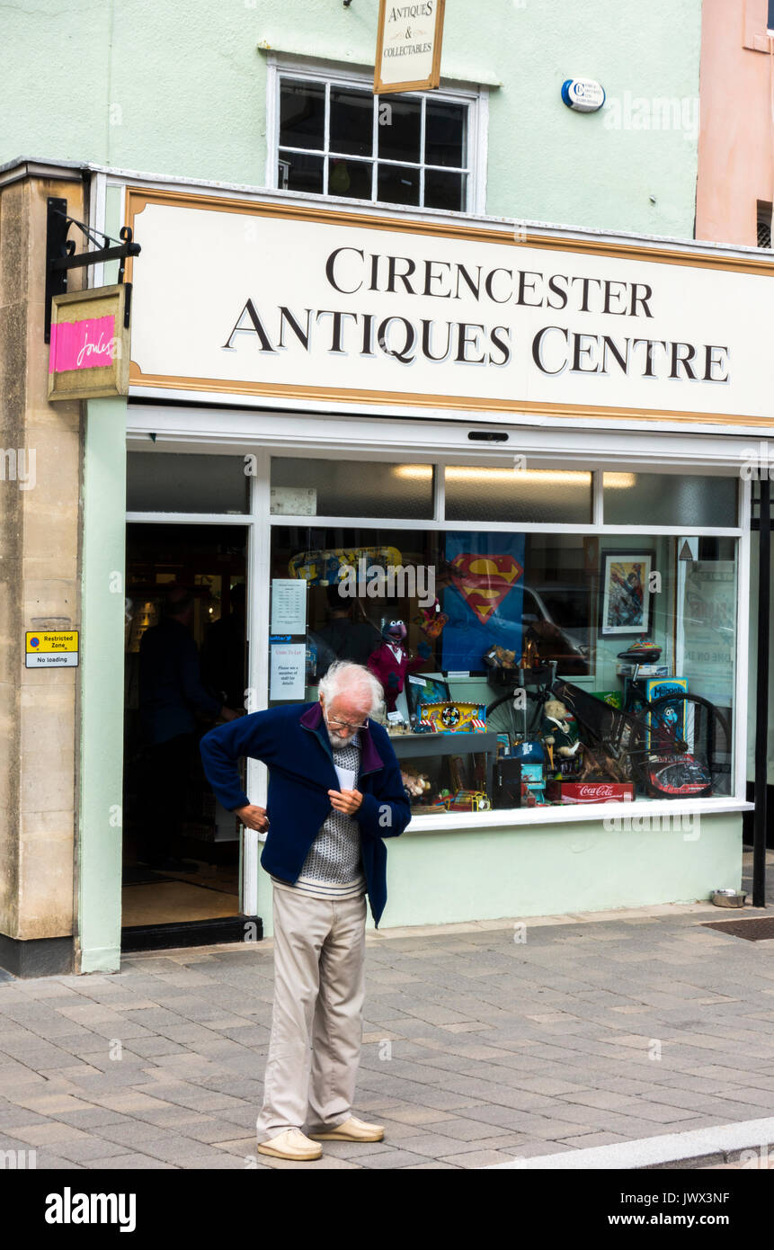 Un vecchio / anziani / senior uomo in piedi al di fuori del centro di antiquariato in Cotswolds città di CIRENCESTER, GLOUCESTERSHIRE, Inghilterra, Regno Unito. Foto Stock