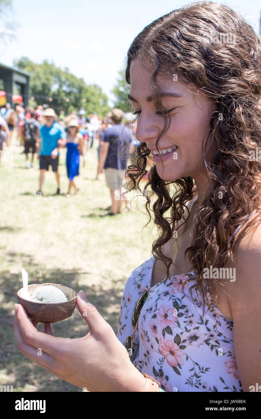 Giovane donna marrone con capelli ricci di prendere una cucchiaiata di gelato presso la Austin Gelato Festival. Foto Stock