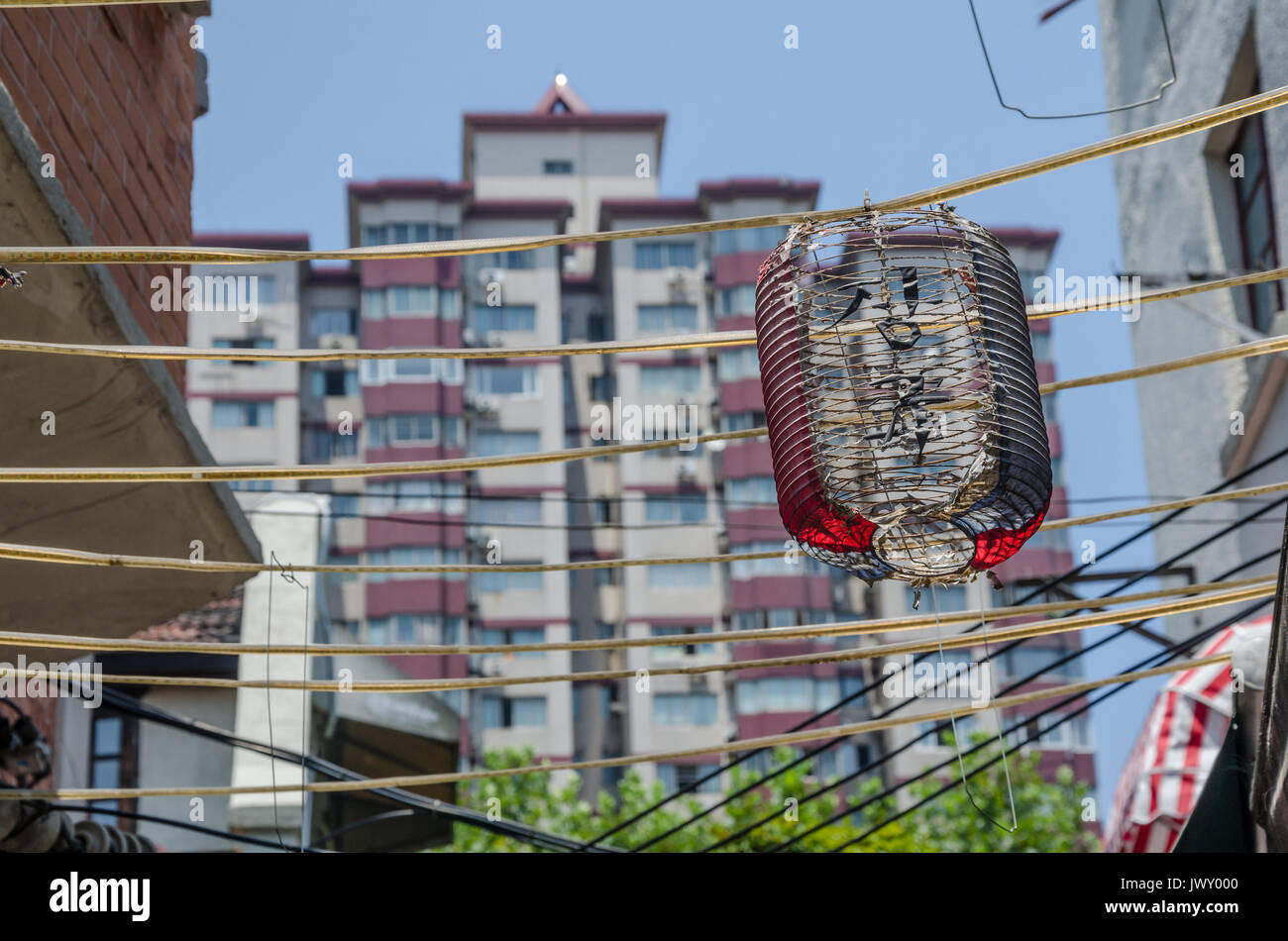 I resti di una lanterna cinese ancora appeso dal cavo di alimentazione che cris-attraversare la strada overhead. Sullo sfondo di un blocco a torre alto e telai. Foto Stock
