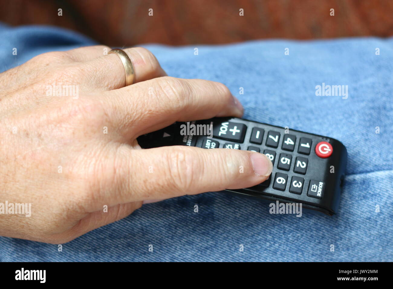 Mano d'uomo tenendo premuto il telecomando del TV. Foto Stock