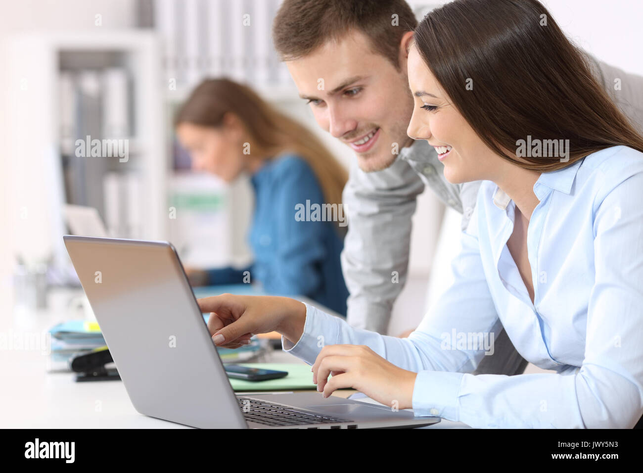 Due colleghi felice coworking on line insieme con un computer portatile in ufficio Foto Stock