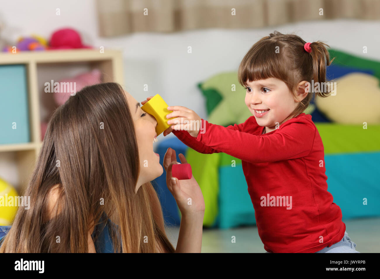 Felice figlia gioca con sua madre sul pavimento di una stanza in casa Foto Stock