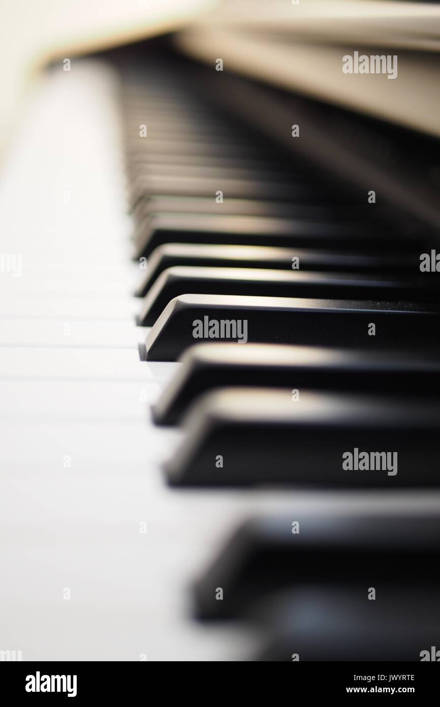 Tastiera di pianoforte. In prossimità dei tasti neri, con un sacco di bokeh di fondo. Foto Stock