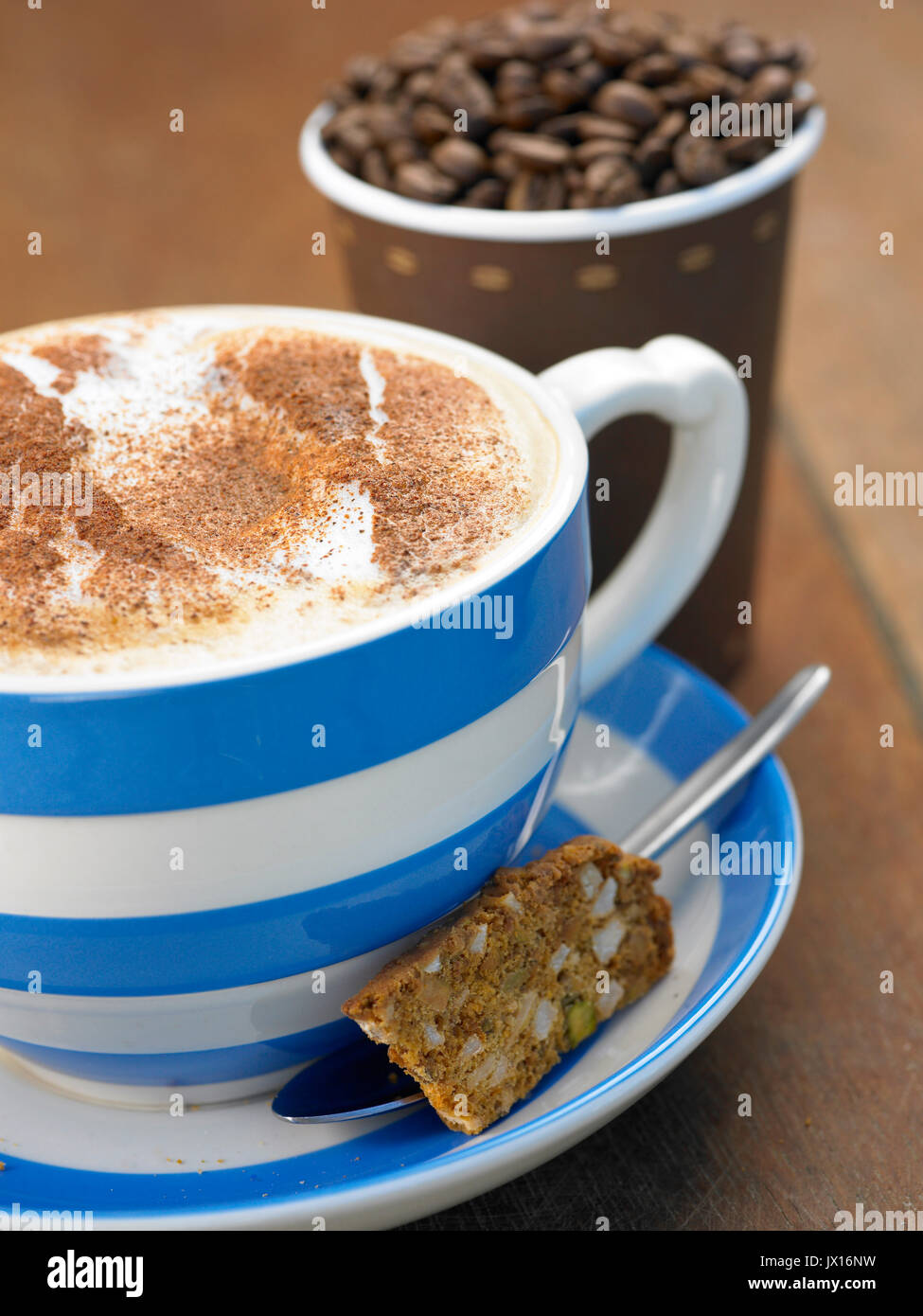 Caffè cappuccino nel grande blu e bianco mug con cannella con pasti da asporto coppa piena di fagioli ,quotidiano e biscotti Foto Stock