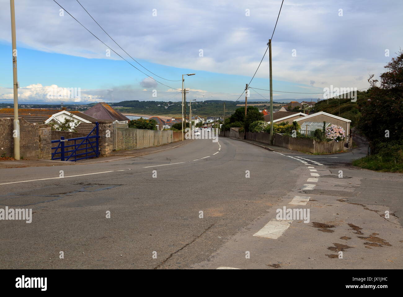 Guardando lungo la strada principale di Ogmore via mare con le case su entrambi i lati e le automobili parcheggiate lungo la strada principale di questo frequentata località turistica. Foto Stock