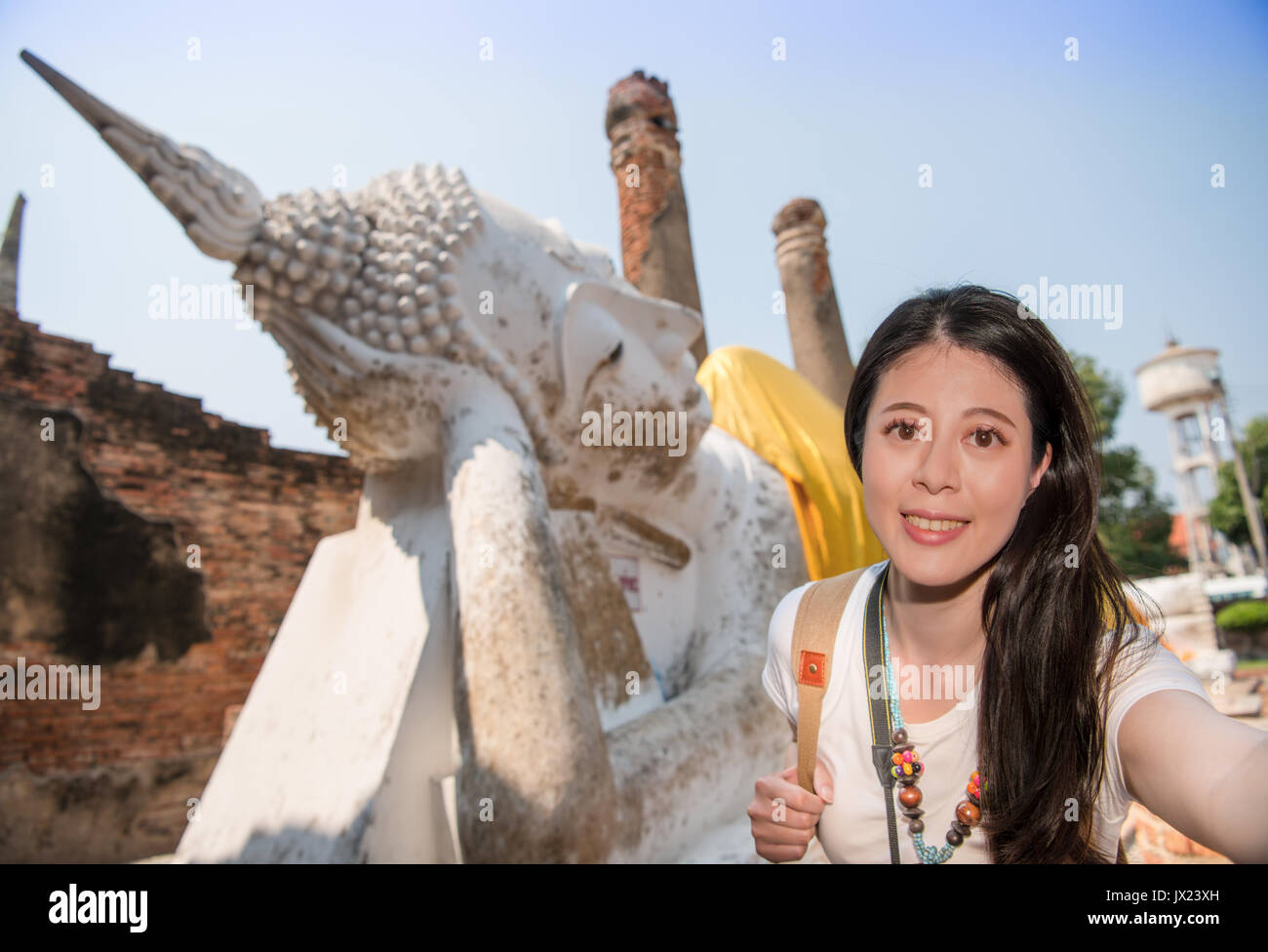 Asia Travel donna backpacker visitando il villaggio di Ayutthaya a Bangkok, in Thailandia e scatta foto selfie sorridenti con il Wat Yai Chai Mongkhon utilizzando mobi Foto Stock