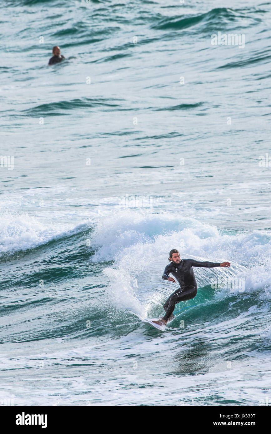 Navigare in UK. Un surfista a cavallo di un onda al Fistral in Newquay, Cornwall. Foto Stock