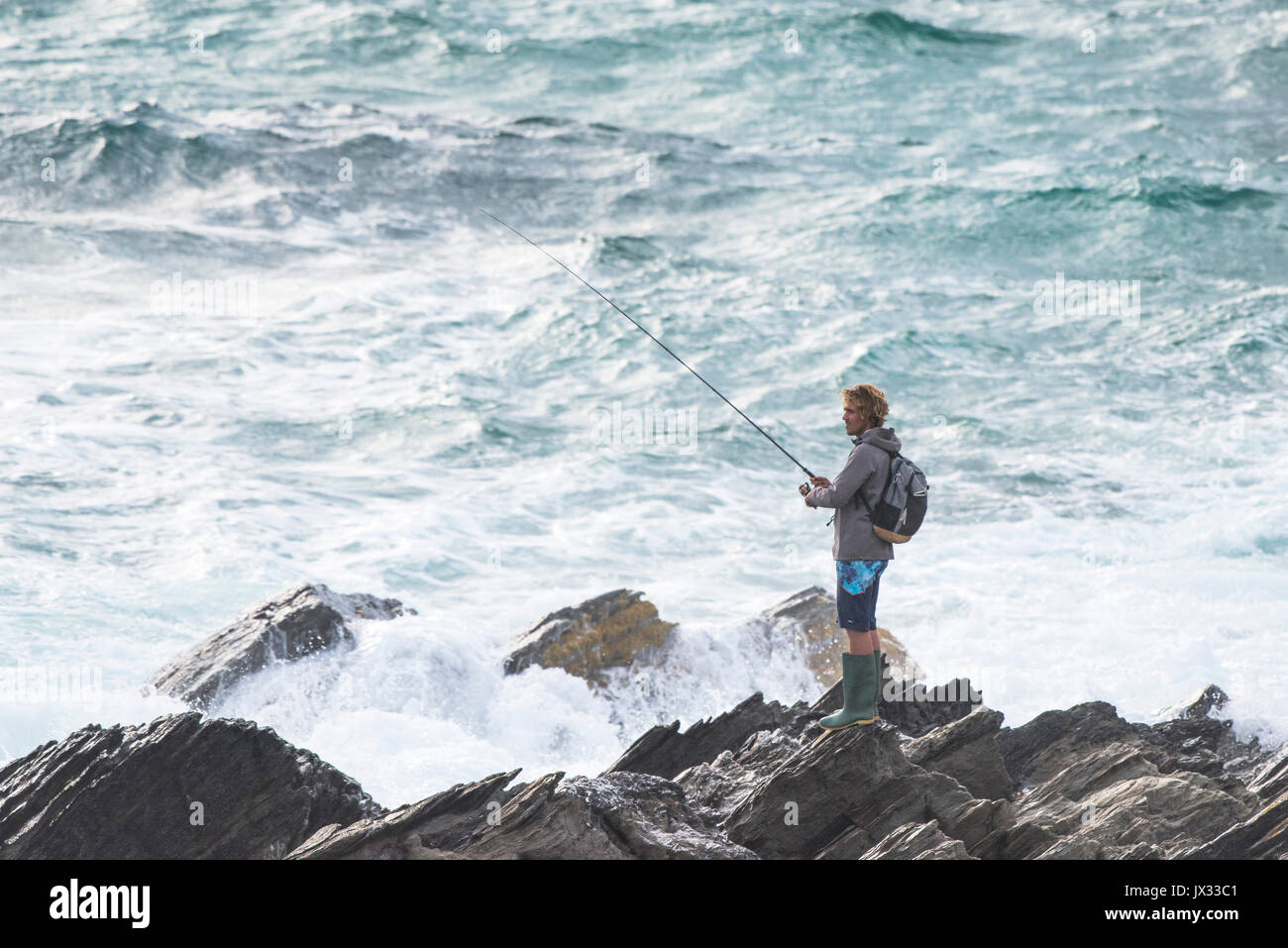 Un pescatore che pesca dalle rocce, Newquay Cornwall. Foto Stock