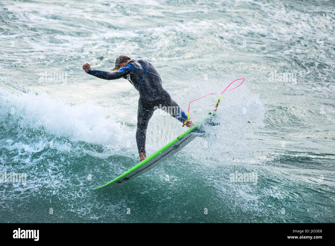Navigare in UK. Un surfista a cavallo di un onda al Fistral in Newquay, Cornwall. Foto Stock
