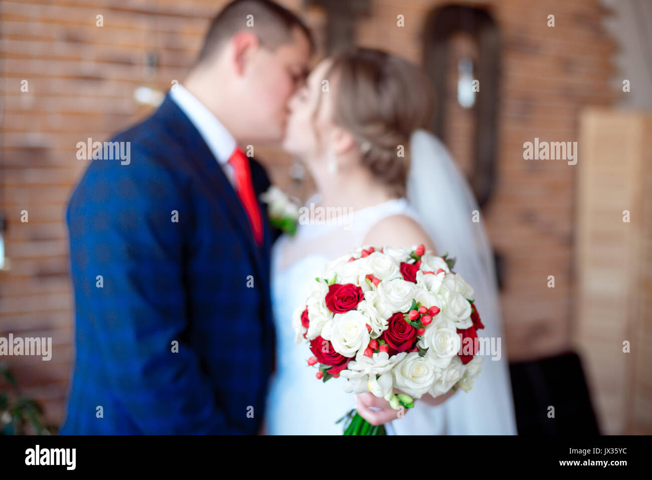 Coppie in viaggio di nozze kissing holding bouquet di fronte a se stessi Foto Stock