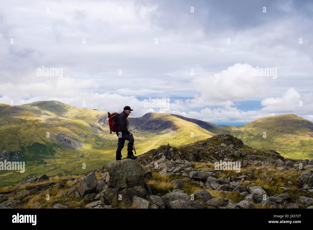 Escursionista maschio su Gallt yr Ogof Rocky Mountain top nel Parco Nazionale di Snowdonia con Carneddau montagne sulla skyline al di là Ogwen Valley. Conwy Wales UK Foto Stock