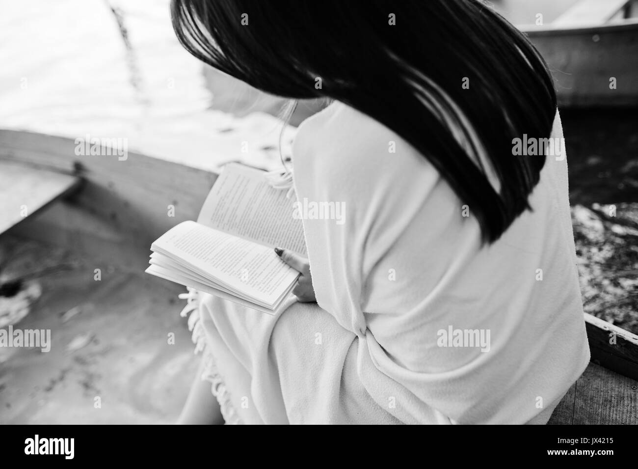 Close-up foto di donna con la schiena durante la lettura di un libro in una barca. Foto in bianco e nero. Foto Stock