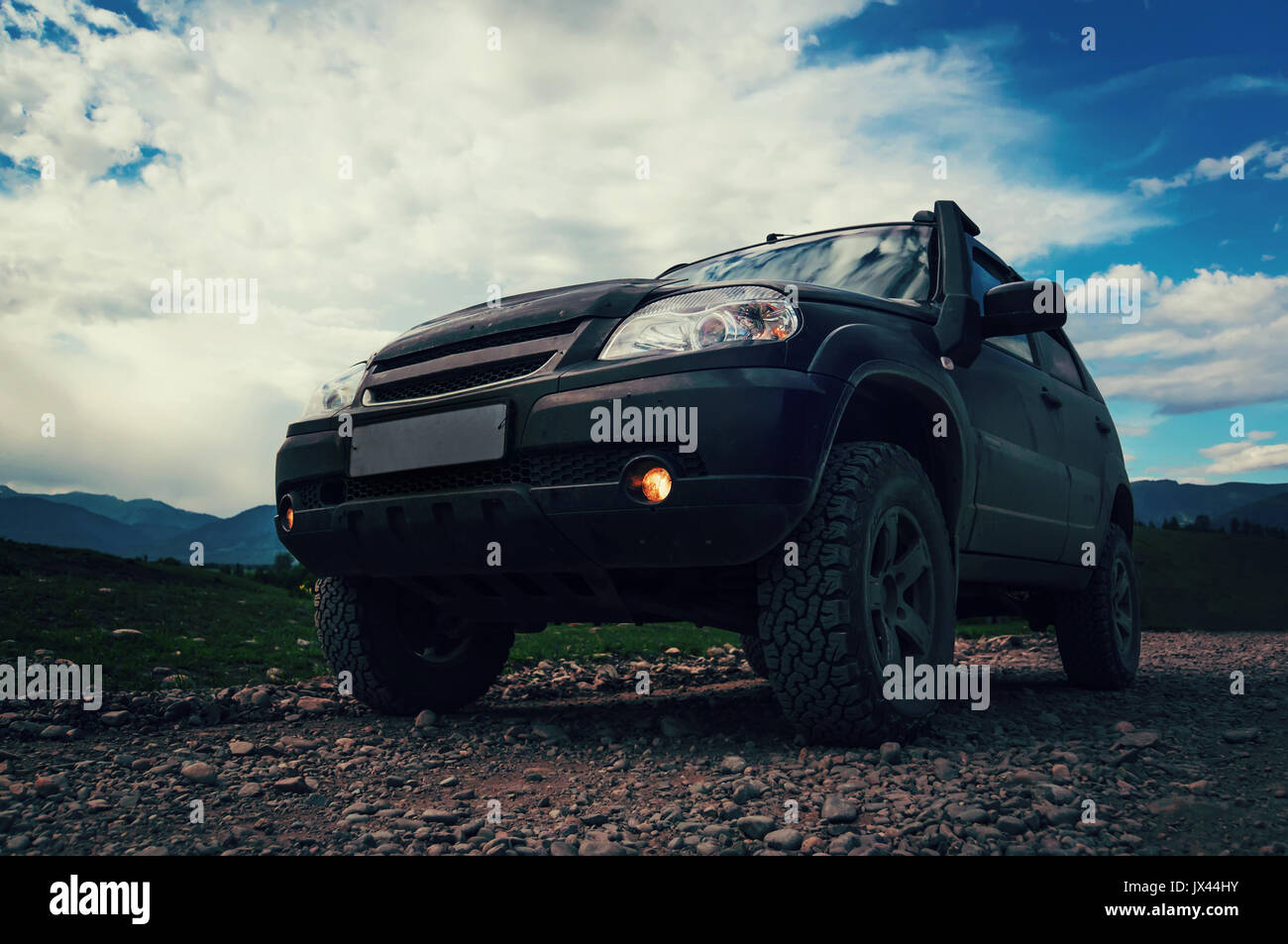 Off-road auto Jeep sulla cattiva strada di ghiaia. Il SUV in primo piano, sulla strada di pietra di ghiaia. Foto Stock