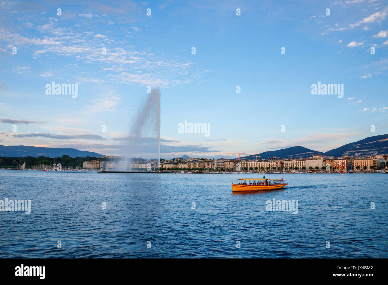 Giallo traversata in battello sul Rodano con edifici lungo il Quai Gustave-Ador sull'altro lato durante il tramonto. Ginevra, Svizzera. Foto Stock