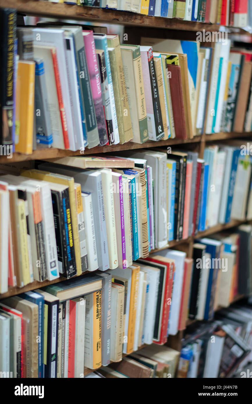 Libri usati impilati su ripiani, in un piccolo book store Foto Stock