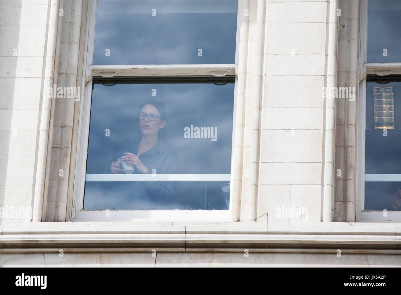 Londra, Regno Unito. 14 Agosto, 2017. Una donna guarda fuori dalla finestra presso il Lincoln Center, il luogo per l'assemblea ordinaria della compagnia mineraria britannica Vedanta, a una protesta al di fuori dagli attivisti dalla lamina Vedanta e altri gruppi protesta come parte di una giornata di azione globale contro la società per evidenziare il suo presunto abuso dei diritti umani, l'evasione fiscale e dell'inquinamento. Altre proteste sono state programmato per avere luogo in Zambia e in India. Credito: Mark Kerrison/Alamy Live News Foto Stock