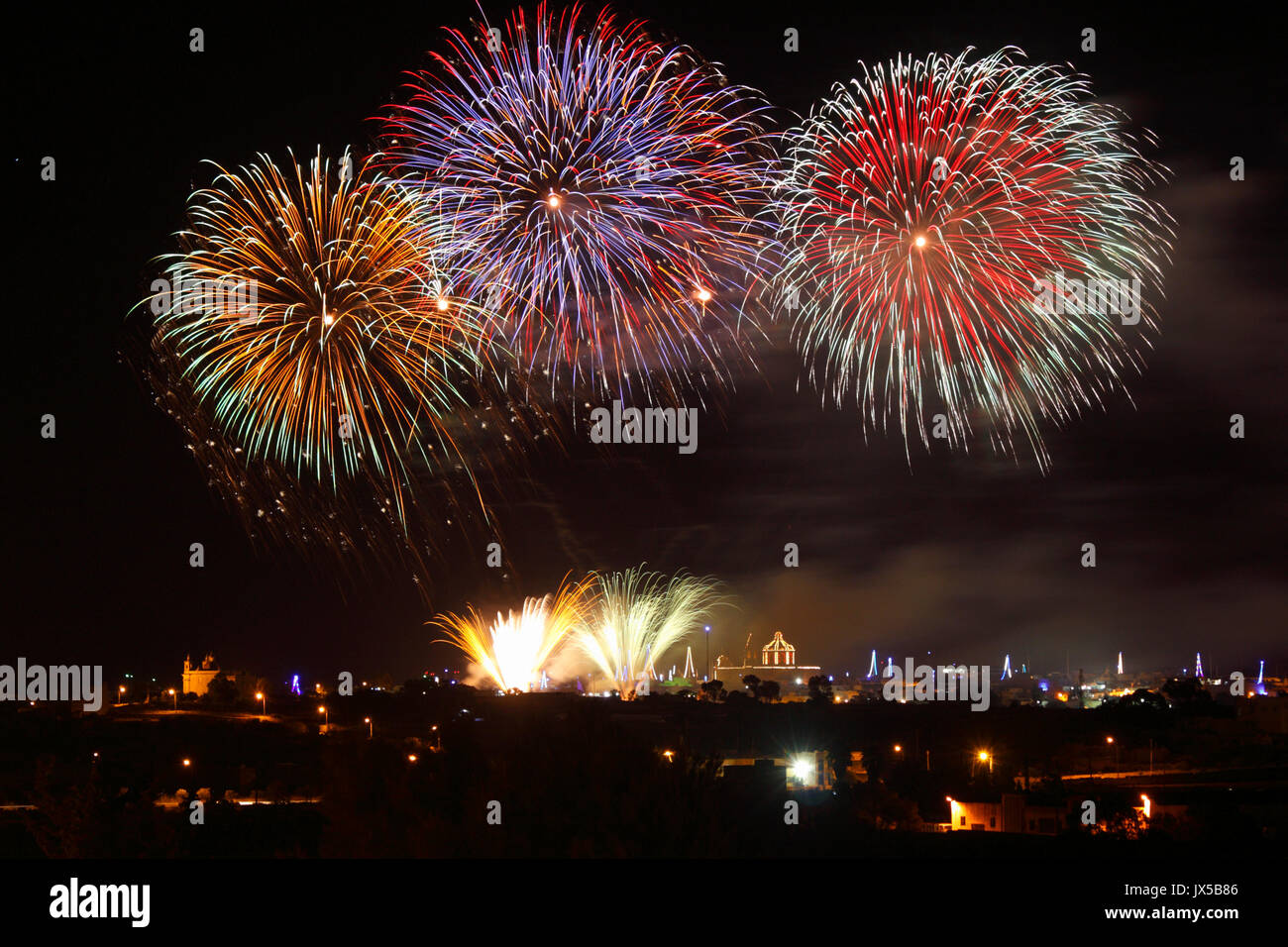 Fuochi d'artificio esplodere sopra la chiesa del villaggio Ghaxaq in Malta alla vigilia dell Assunzione, una data importante per la Chiesa Cattolica Romana calendario religioso e quello che si celebra ogni anno da diverse città Maltese e villaggi Foto Stock