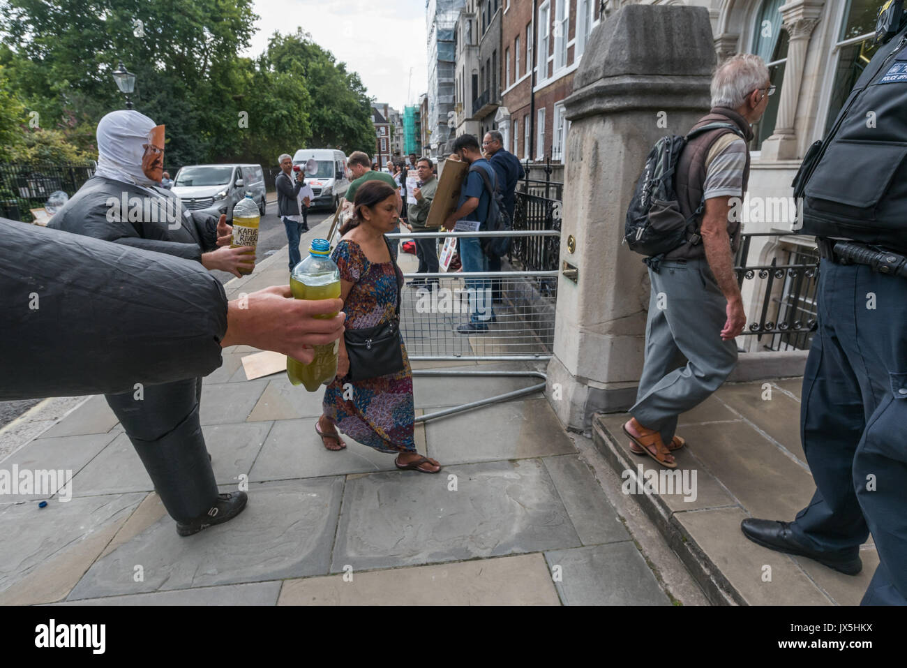 Londra, Regno Unito. 14 Ago, 2017. Londra, Regno Unito. Il 14 agosto 2017. Le persone che frequentano la Vedanta AGM ignora i due uomini vestiti in tute gonfiabili con maschere di proprietario del Vedanta Anil Agarwal e amministratore delegato Tom Albanese tenendo la bottiglia di acqua inquinata dal fiume Kafue nello Zambia. Lamina accusano la Vedanta Vedanta di estrazione illegale in Goa, crescente di vessazioni, torture e false accuse contro gli attivisti tribali in Nyamgiri, Odisha, che hanno utilizzato le leggi indiane per interrompere la bauxite della loro montagna sacra, undici anni di rovinosa e continuo inquinamento da Konkola miniere di rame (KCM) in Zambia, dove Foto Stock