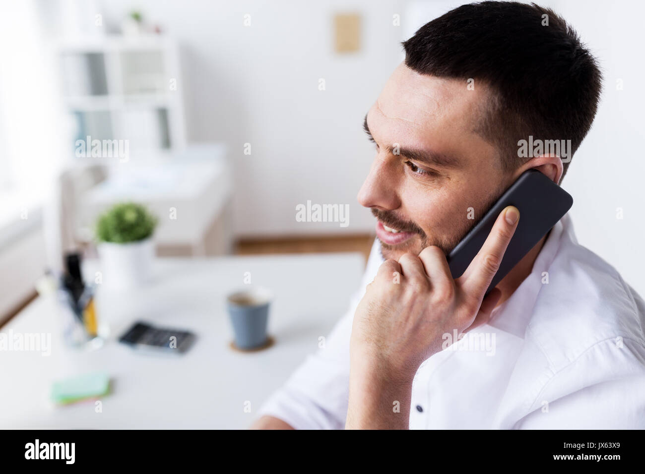 Imprenditore chiamando sullo smartphone in ufficio Foto Stock