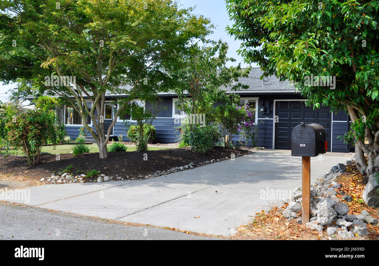 Esterno di una singola storia rambler home verniciato grigio con rivestimento bianco. Graziosa piccola casa residenziale dalla street view. Foto Stock