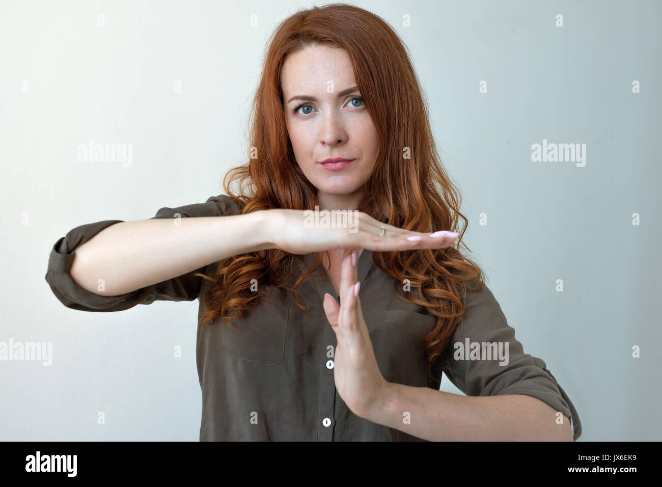 Giovane donna che mostra il tempo fuori mano gesto, frustrato urlando per arrestare isolato sul muro grigio Sfondo. Foto Stock