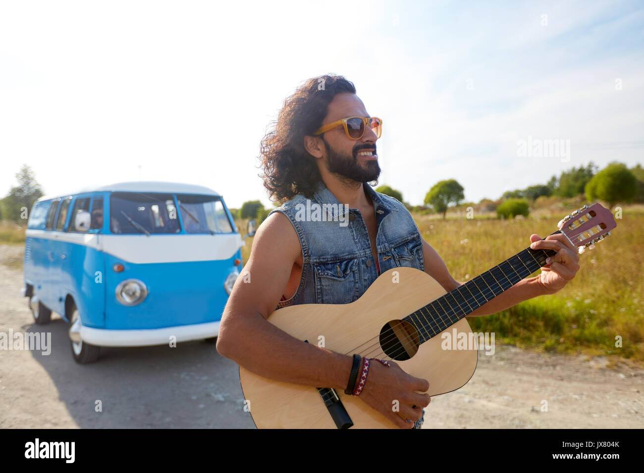 Hippie uomo a suonare la chitarra in minivan auto all'aperto Foto Stock