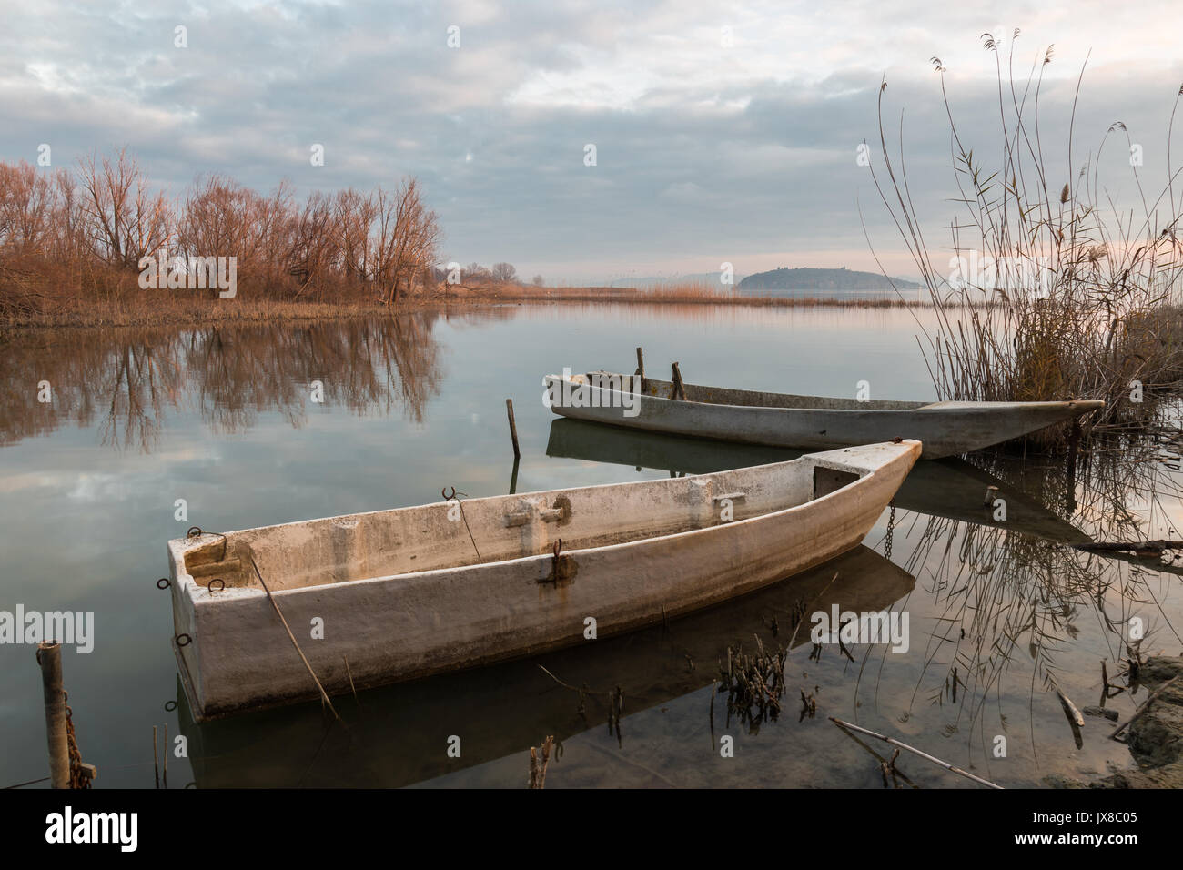 Alcune piccole barche da pesca sul lago a quasi il tramonto, con bellissimo Cielo e nubi riflessi su acqua ancora Foto Stock