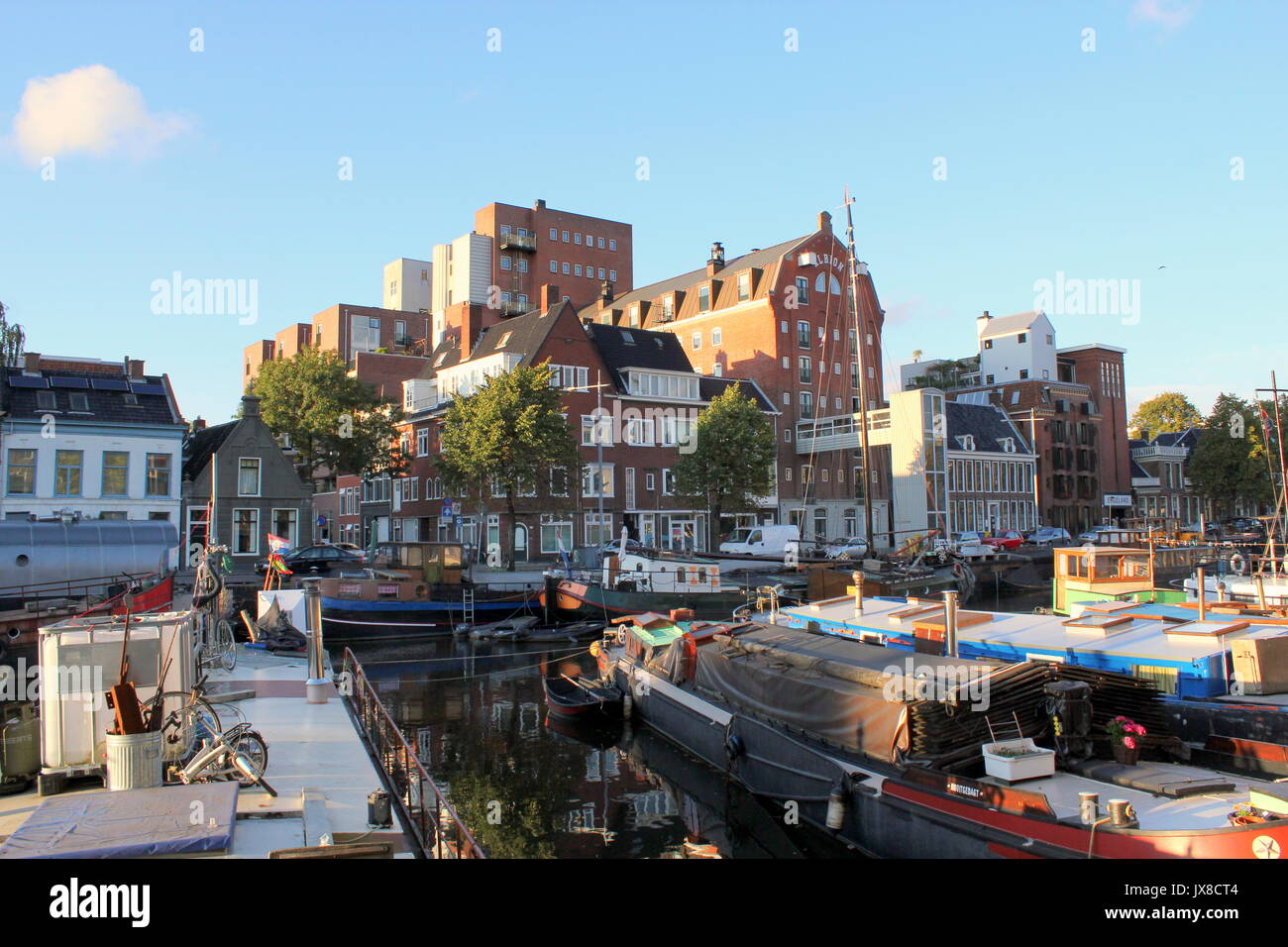 Complesso di appartamenti ex magazzino Albion a Noorderhaven canal a Groningen, Paesi Bassi. Vecchie navi a vela e case galleggianti ormeggiate nella parte anteriore. Foto Stock