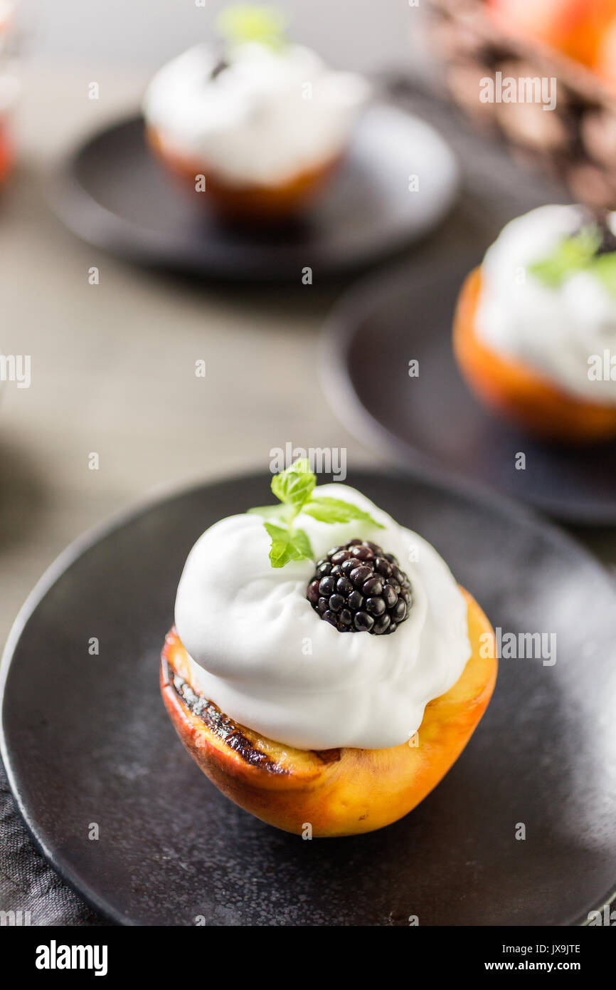 Grigliata peachs organico con la panna montata e guarnita con menta fresca. Foto Stock