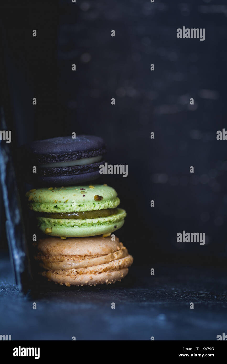 French macarons o amaretto su sfondo scuro. Primo piano di messa a fuoco selettiva Foto Stock
