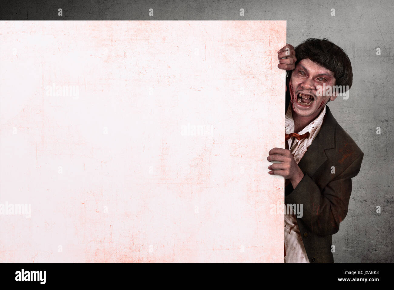 Ritratto di zombie asiatici uomo azienda vuoto banner bianco su sfondo grunge Foto Stock