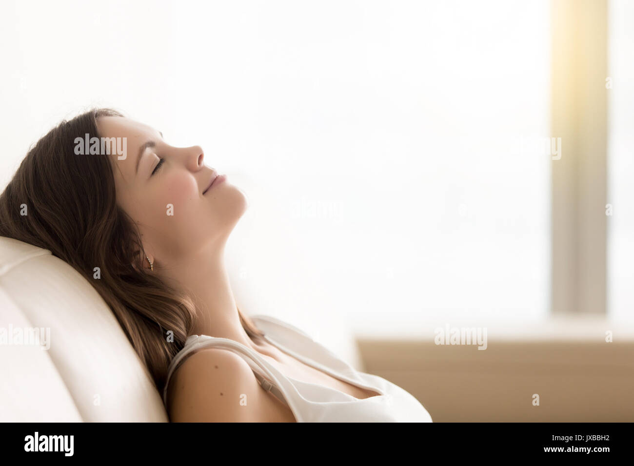 Rilassata giovane donna godendo di poggiare su un comodo divano, copia spac Foto Stock