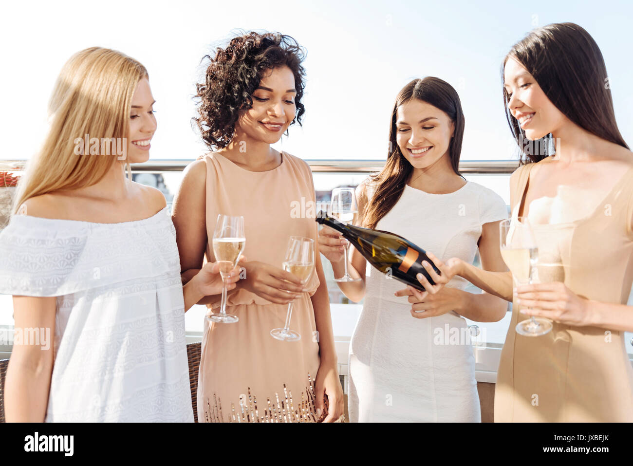 Gioioso donna positivo versando champagne Foto Stock