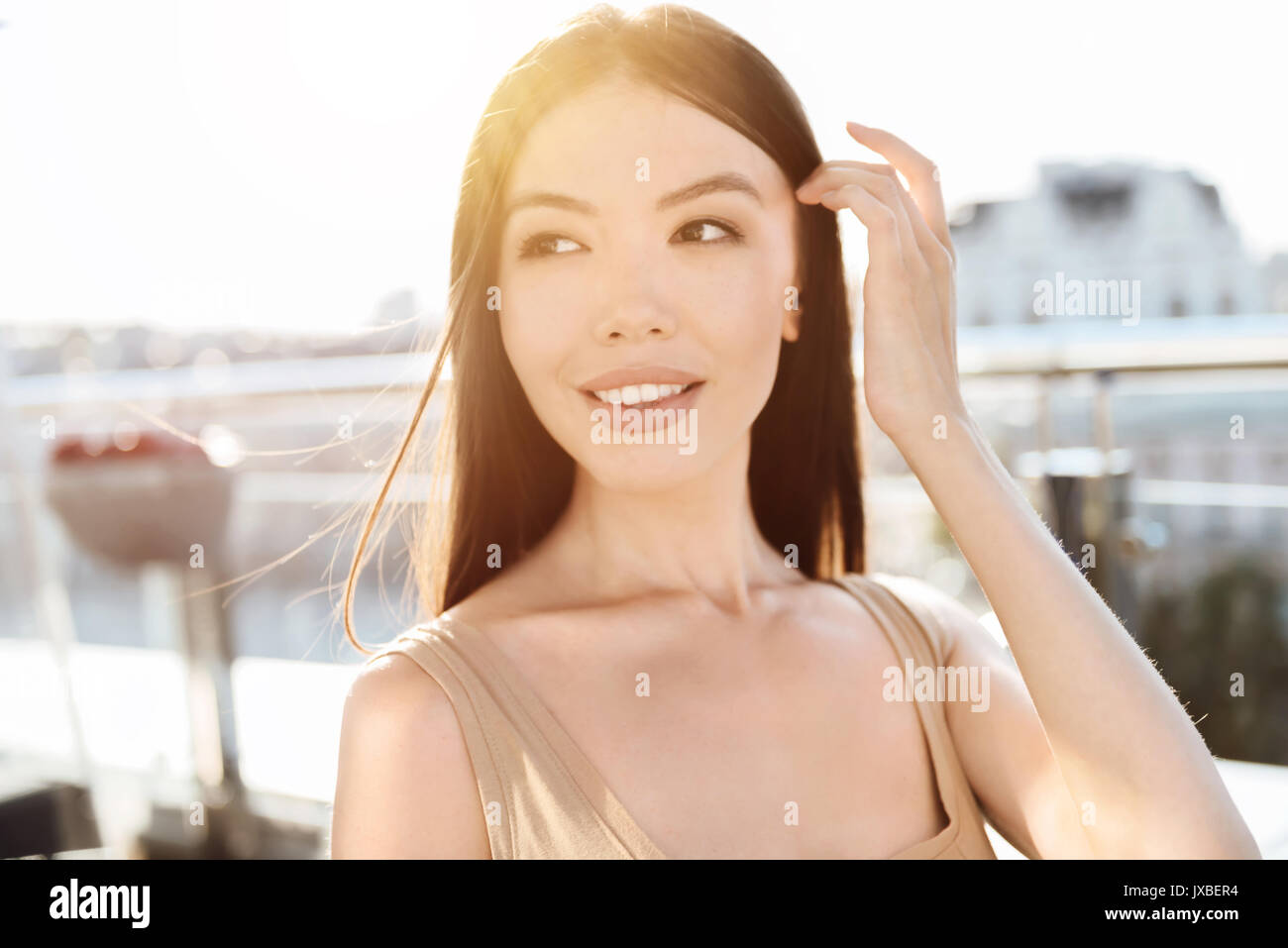 Felice sognante donna che fissa i suoi capelli Foto Stock