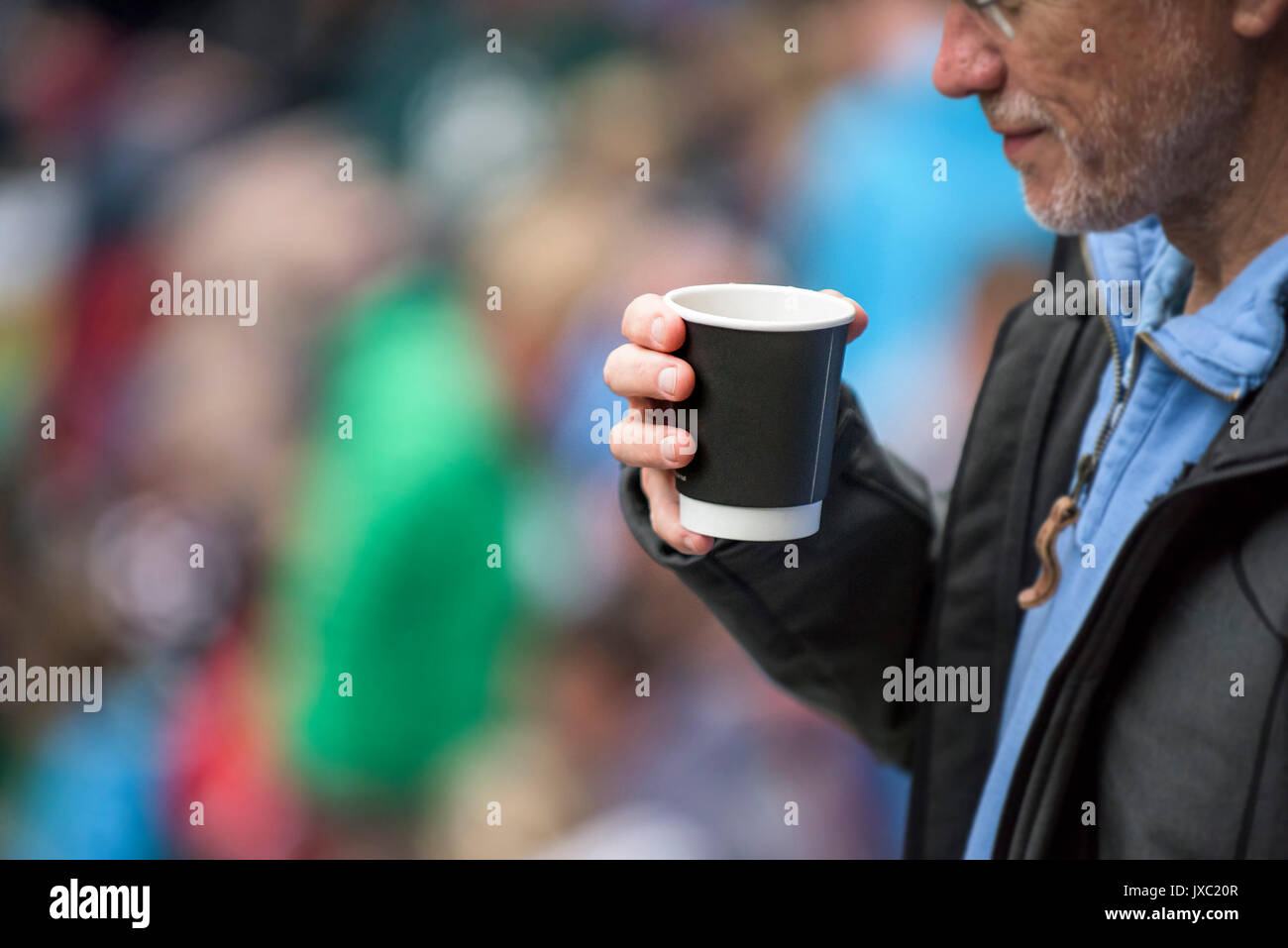 Un uomo di bere il caffè fuori di una tazza monouso. Foto Stock