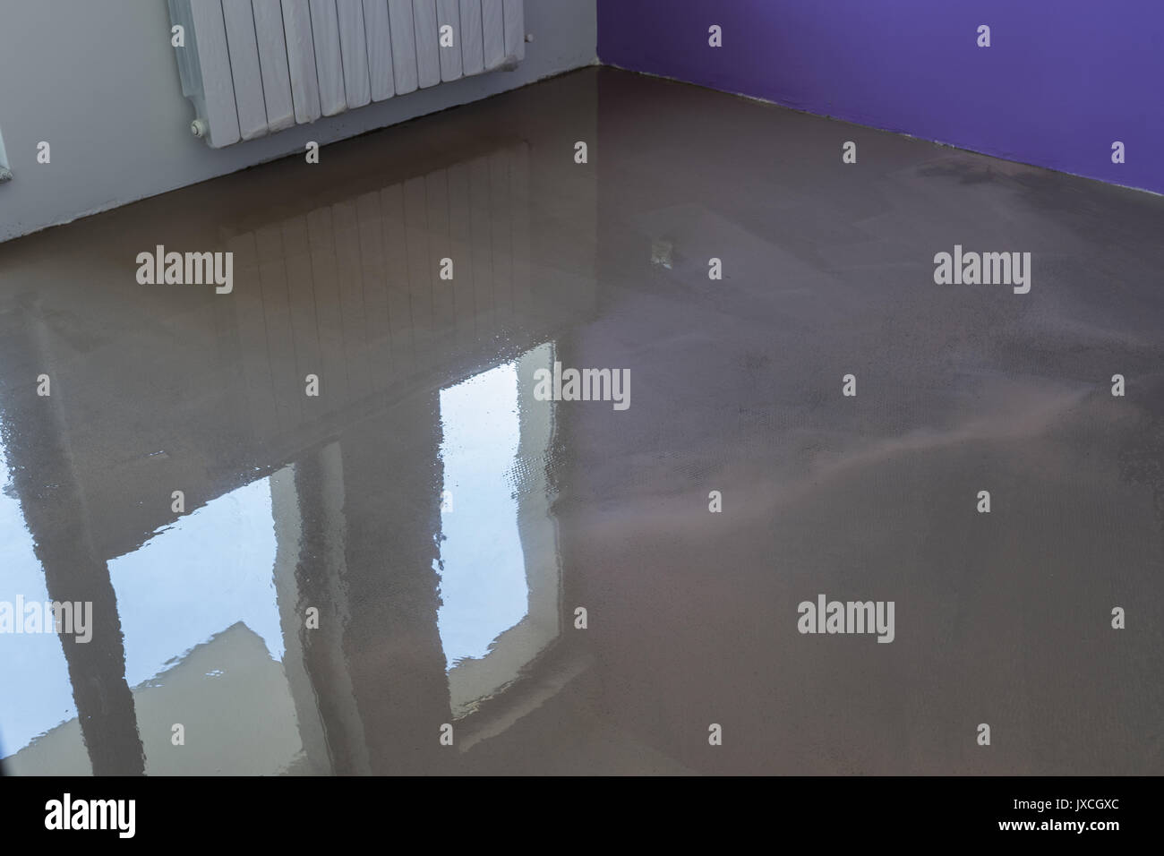 Interno dell appartamento in costruzione. La copertura del pavimento con autolivellamento malta di cemento. Specchio liscia della superficie del pavimento Foto Stock