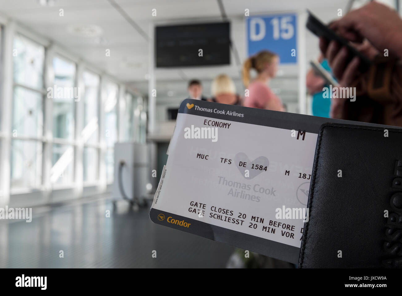 I passeggeri in possesso di carta di imbarco in attesa al gate di partenza a bordo di un volo all'aeroporto di Monaco di Baviera, Germania Foto Stock