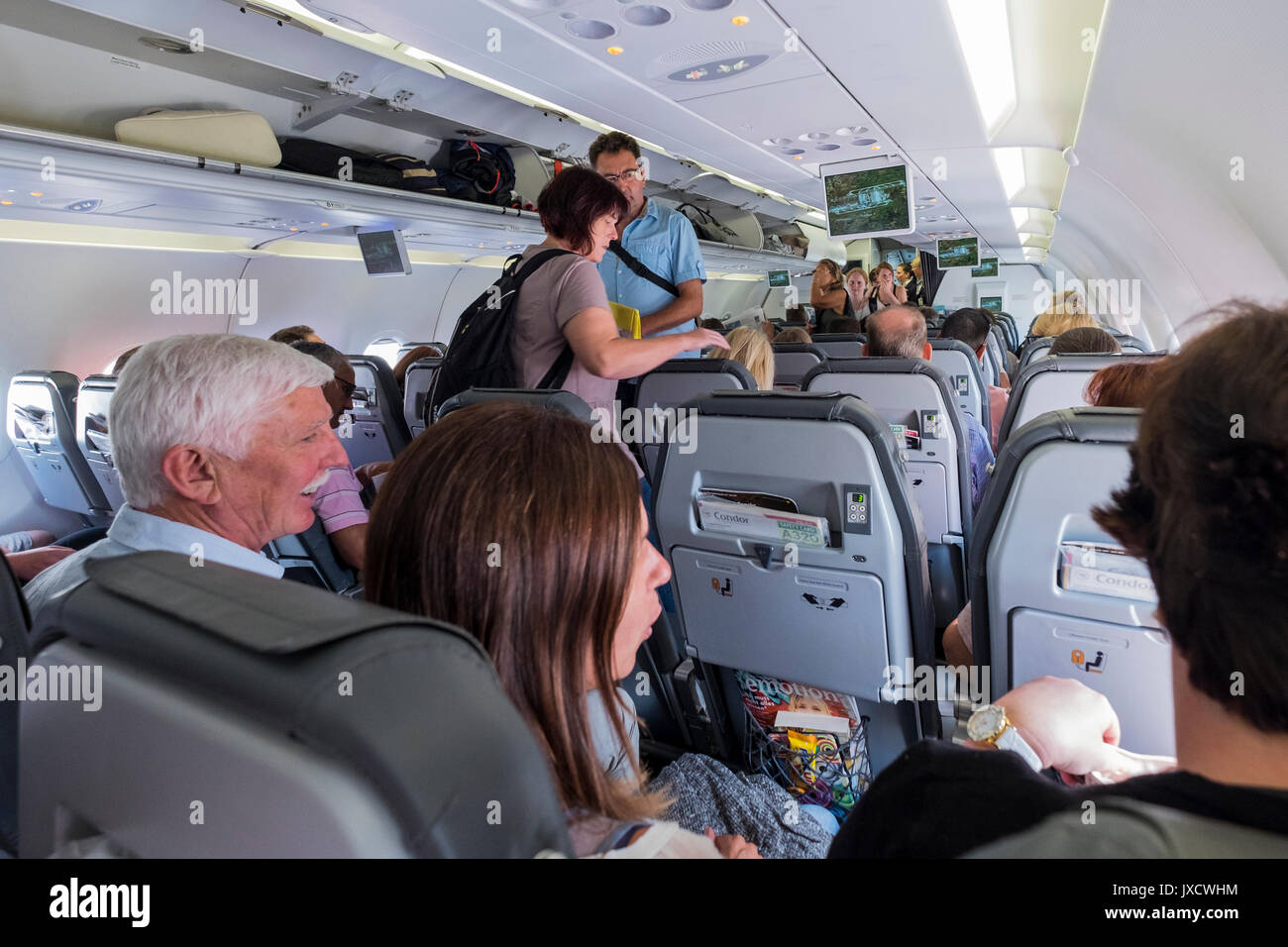 I passeggeri di salire a bordo di un condor, Thomas Cook Airlines, volo, Airbus A320 nel corridoio di andare alla loro sede e riporre i bagagli a mano in overhead Foto Stock