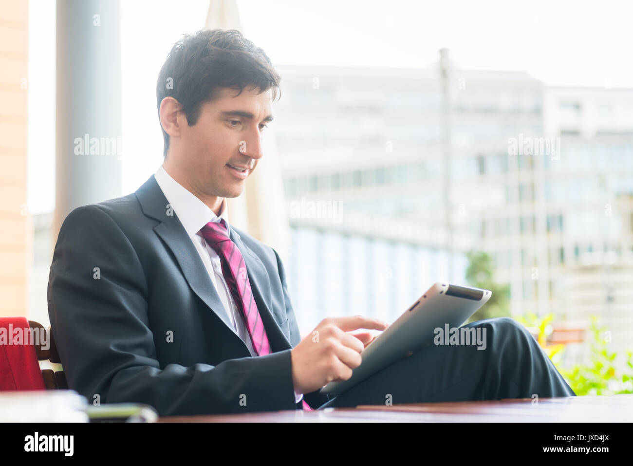 Giovane uomo che indossa business suit durante l'utilizzo di un tablet PC durante il b Foto Stock