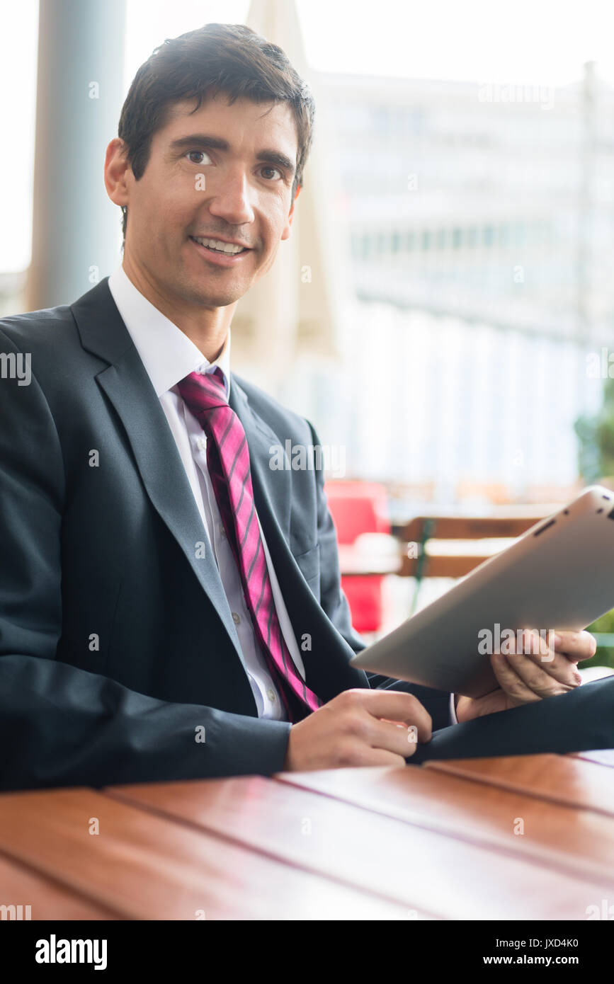 Giovane uomo che indossa business suit durante l'utilizzo di un tablet PC durante il b Foto Stock