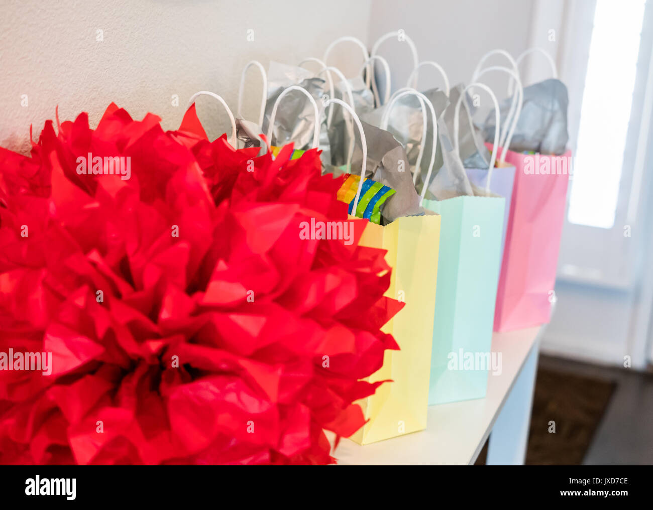 Color pastello party buste regalo con un grande rosso della decorazione impostato su un piccolo tavolo. Foto Stock