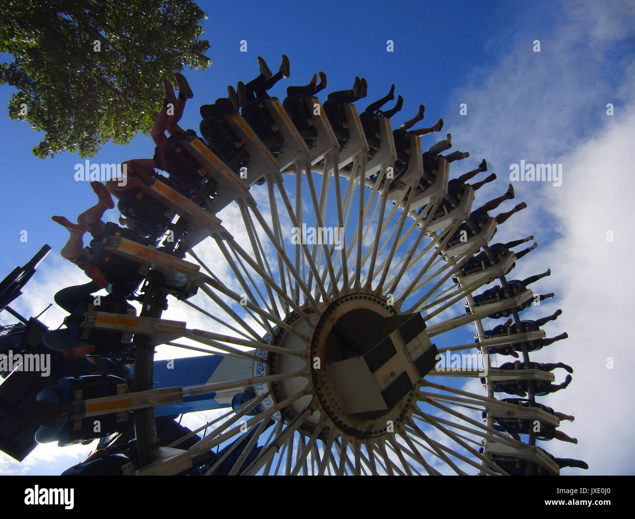 Un sacco di persone sulla circolare spaventoso fairground ride con struttura ad albero e cieli blu appena le gambe nel cielo Foto Stock