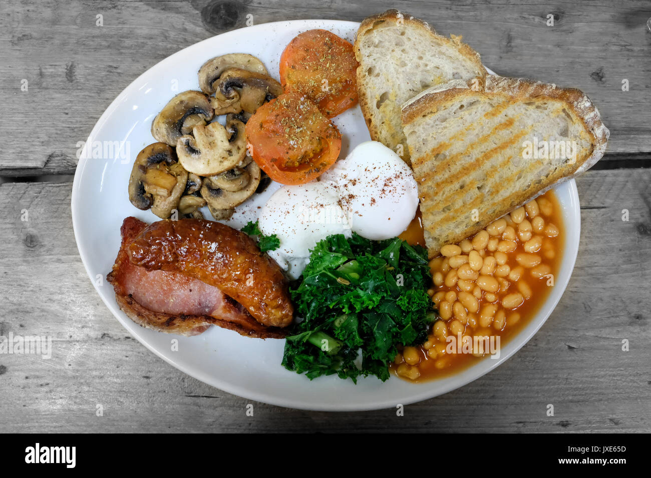 Una sana alternativa alla tradizionale colazione inglese completa con uova in camicia, pomodori, salsicce, pancetta, funghi e kale Foto Stock