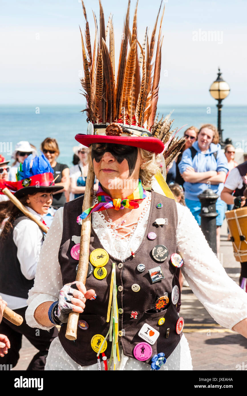 Inghilterra, Broadstairs settimana della musica folk. Cavallo morto e il broomdashers Morris lato. Una donna dalla Broomdashers ballare mantenendo lo staff di legno. Indossando il cofano con piume su. E la gente di mare in background. Foto Stock