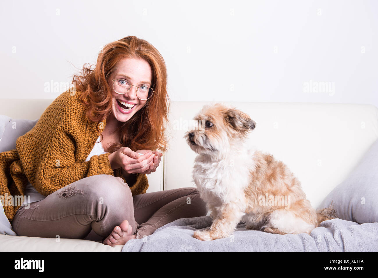 Bellissimi i capelli rossi donna educa il suo cane sul lettino Foto Stock