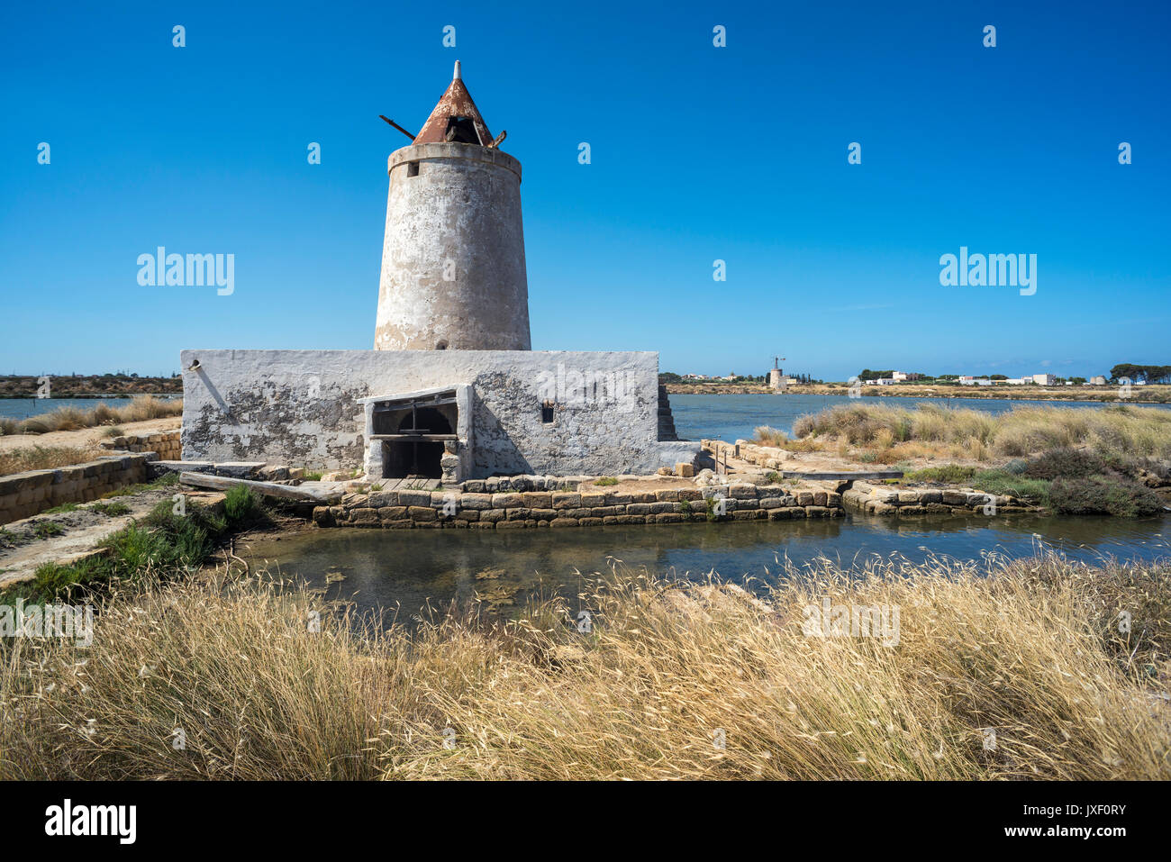 Saline e mulino a vento abbandonati alla Salina grande riserva naturale vicino Culcasi, a sud di Trapani, sulla costa occidentale della Sicilia, Italia. Foto Stock