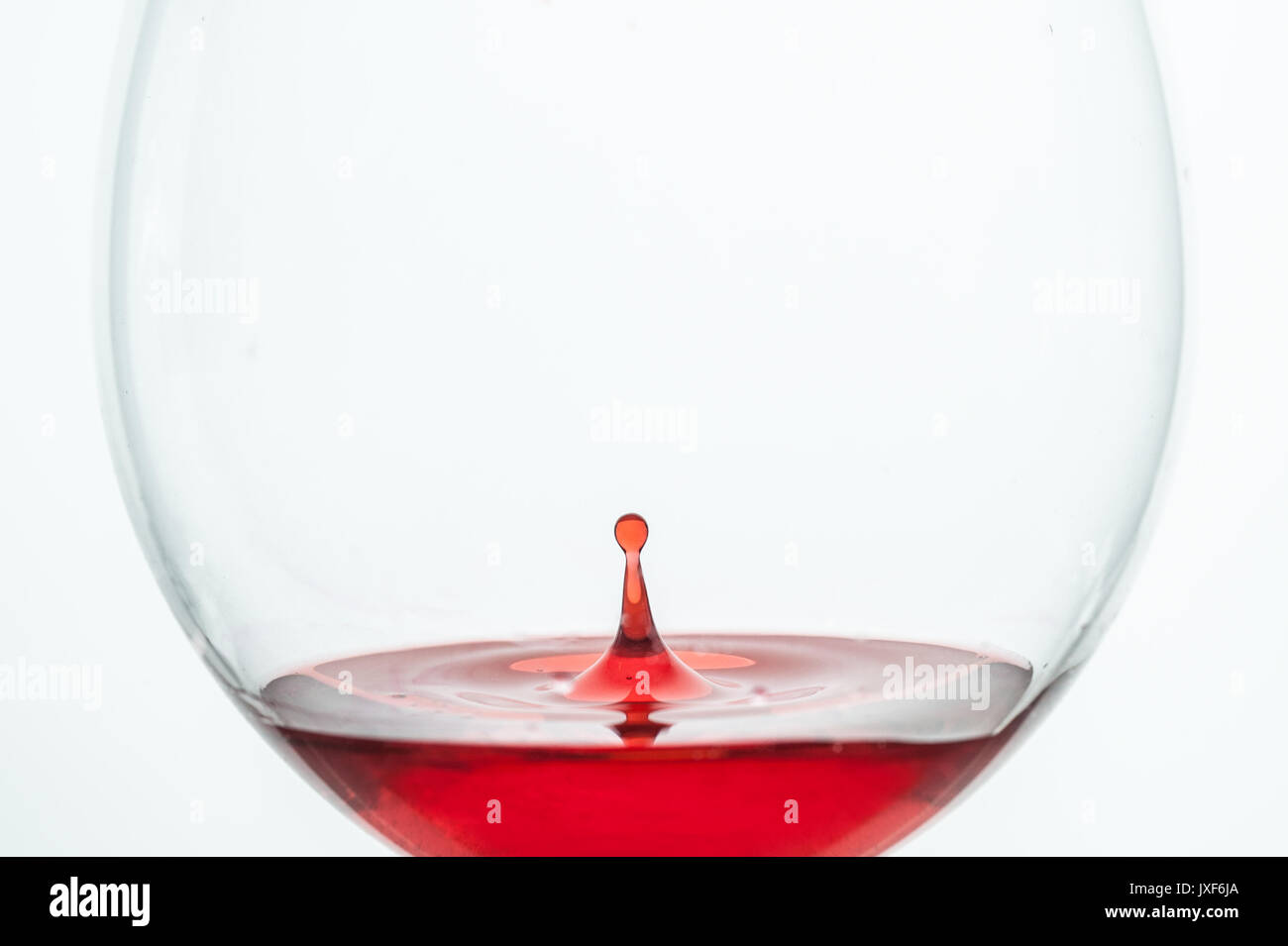 Il rimbalzo delle goccioline in un bicchiere da vino formando un leggero splash Foto Stock